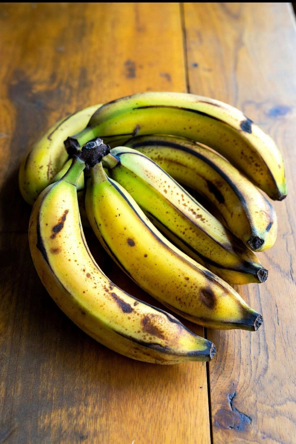 Solid Cargo GmbH - Internationalen Handel - Ein Bündel reifer, gelber Bananen mit braunen Flecken liegt auf einer Holzoberfläche.
